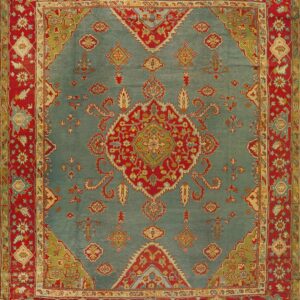 Traditional ornate rug with a blue field, red border, and complex floral medallion design.
