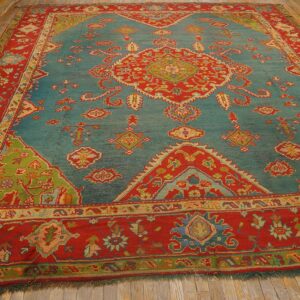Ornate teal rug with red borders, a central medallion, and lime green corner accents on wood floor.