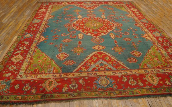 Ornate teal rug with red borders, a central medallion, and lime green corner accents on wood floor.
