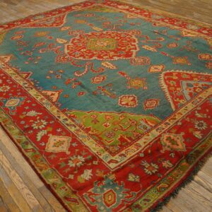 Teal and red traditional patterned rug with lime green accents rests on rustic wood plank flooring.