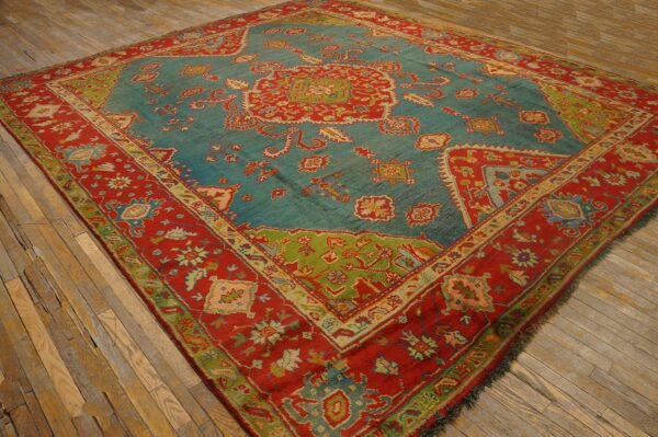 Teal and red traditional patterned rug with lime green accents rests on rustic wood plank flooring.