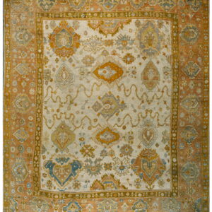 Low-pile rug with geometric patterns in cream, rust, gold, and muted blue tones.