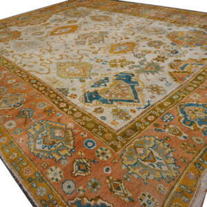 Ornate patterned rug featuring a rust border surrounding an off-white center with blue and gold motifs.