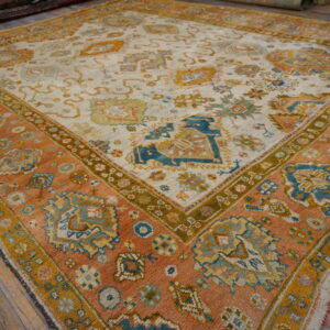 Low-angle view of a large rug featuring terracotta, cream, and teal patterns on wooden planks.