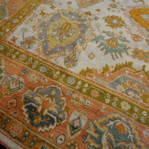 Textured rug featuring apricot, ivory, moss green, and blue-gray traditional geometric and floral motifs.