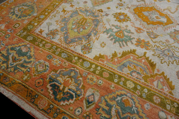 Textured rug featuring apricot, ivory, moss green, and blue-gray traditional geometric and floral motifs.