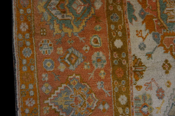 High-pile rug texture with complex traditional patterns in rust orange, cream, moss green, and gold.