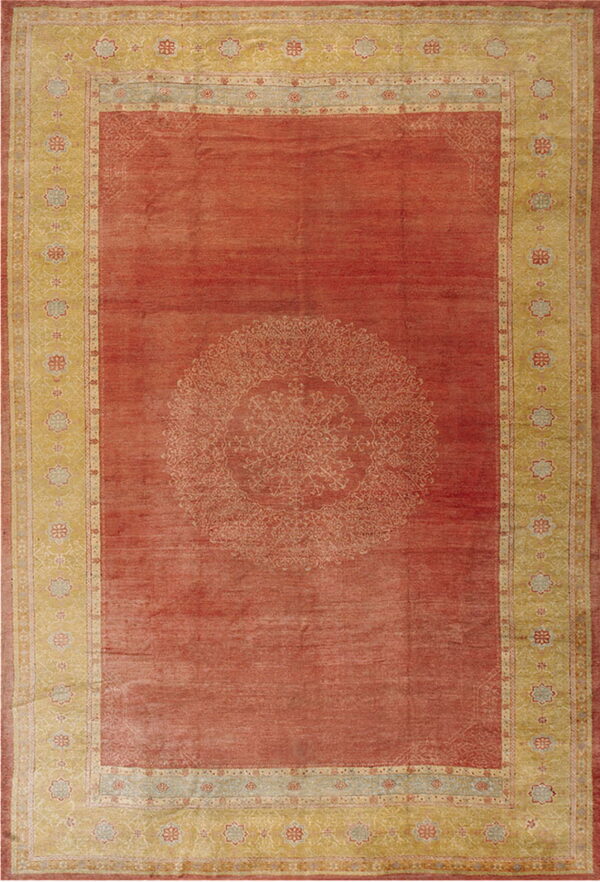 Rust red rug featuring a large central medallion and wide golden-yellow borders with repeating floral motifs.