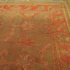 Terracotta and brown rug with stylized geometric patterns rests on distressed yellow wood flooring.