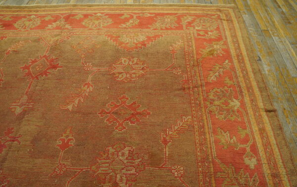 Terracotta and brown rug with stylized geometric patterns rests on distressed yellow wood flooring.