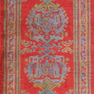 A red runner rug featuring large slate blue and olive geometric medallion patterns with detailed borders.
