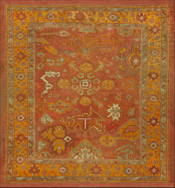 Rust-colored tribal rug with geometric patterns in gold, sage green, and cream accents.