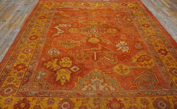 Traditional orange rug with complex gold and taupe geometric patterns rests on old wood planks.