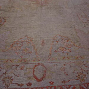 Low-angle view of a distressed rug featuring muted tones and traditional orange and yellow designs.