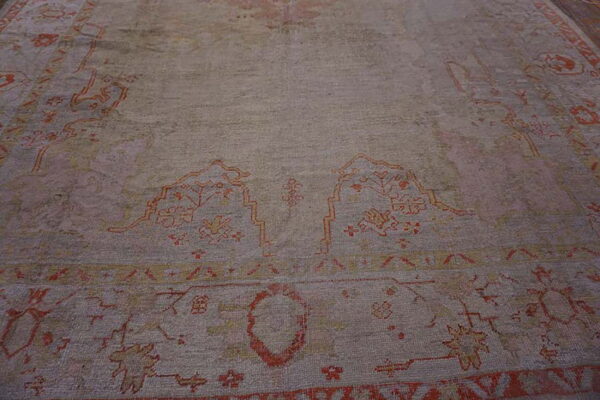 Low-angle view of a distressed rug featuring muted tones and traditional orange and yellow designs.