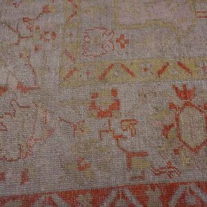 Detail of a low-pile rug featuring geometric tribal patterns in light gray, terracotta, and gold.