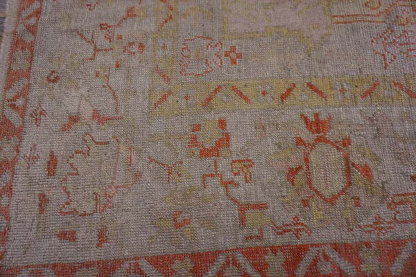 Detail of a low-pile rug featuring geometric tribal patterns in light gray, terracotta, and gold.