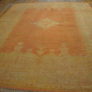 Low pile traditional rug in faded apricot and yellow with a center medallion laid on rustic wood flooring.