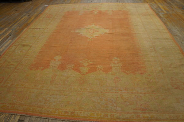 Low pile traditional rug in faded apricot and yellow with a center medallion laid on rustic wood flooring.