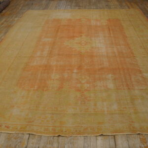 Faded apricot and yellow traditional rug displayed on wide, worn wooden floorboards.