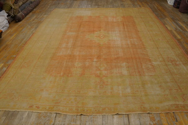 Faded apricot and yellow traditional rug displayed on wide, worn wooden floorboards.