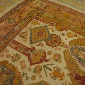 Detailed view of a multicolored rug corner showing rust borders, geometric motifs, and exposed wood floor.