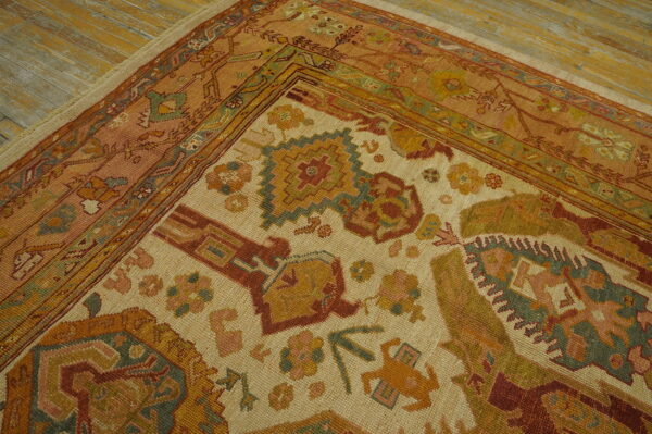 Detailed view of a multicolored rug corner showing rust borders, geometric motifs, and exposed wood floor.