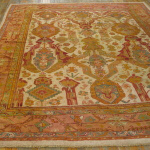 Large area rug with a cream field and tribal patterns in rust, gold, and teal, resting on wood floorboards.