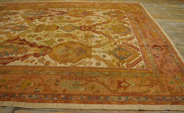 Low-pile rug featuring complex traditional patterns in cream, rust, gold, and pale green on wood flooring.