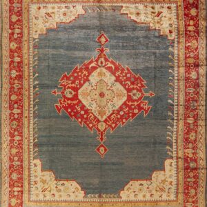 Square rug with a slate blue field, red medallion, and intricate floral red and beige borders.