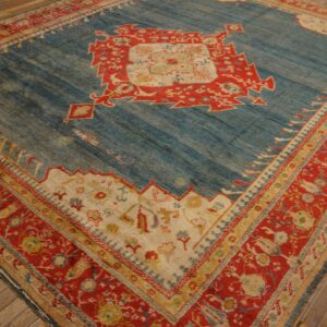 Blue and red geometric rug with a central medallion rests on worn wooden floorboards.
