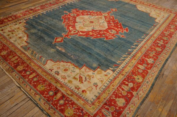 Blue and red geometric rug with a central medallion rests on worn wooden floorboards.