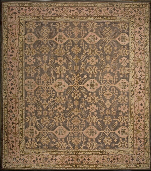 Square rug with a dark field and dense, geometric motifs in dusty pink and pale olive borders.