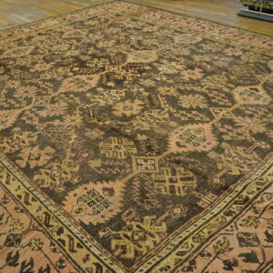 A large brown rug with pink and gold geometric patterns rests on a hardwood floor.