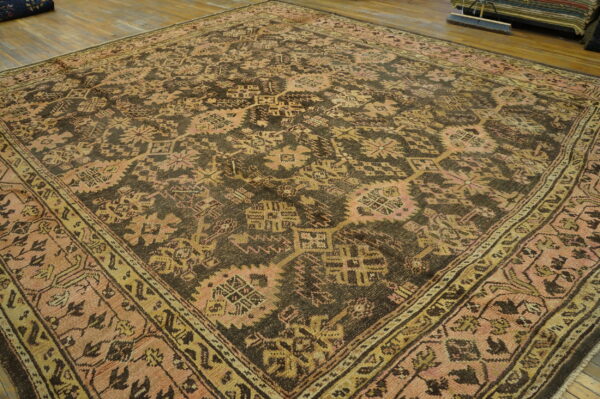 A large brown rug with pink and gold geometric patterns rests on a hardwood floor.