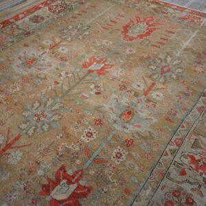 Low-pile area rug with traditional red, gray, and tan botanical patterns rests on distressed plank flooring.