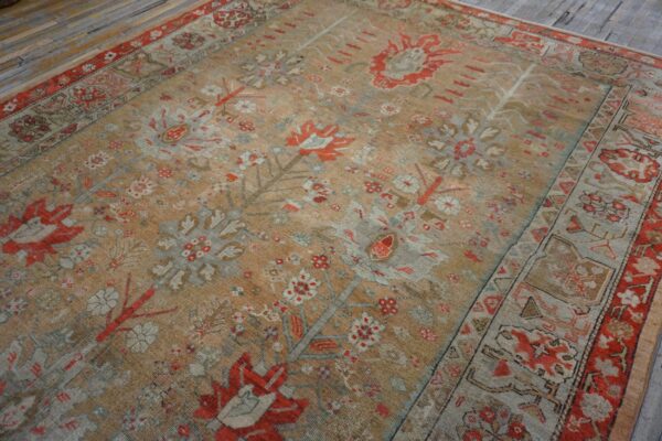 Low-pile area rug with traditional red, gray, and tan botanical patterns rests on distressed plank flooring.