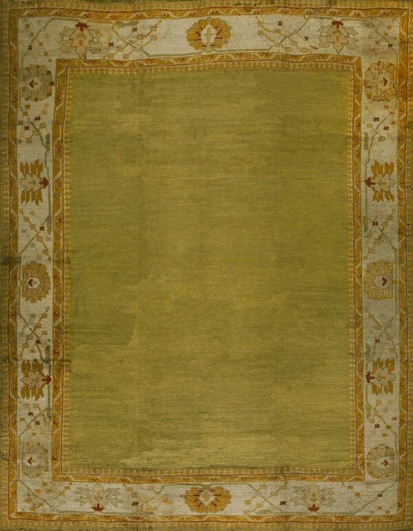 Textured olive green rug with a wide, decorative border featuring pale yellow, cream, and maroon floral designs.