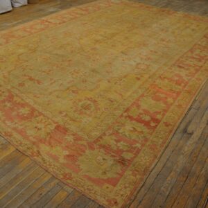 Distressed golden-yellow rug with faded floral patterns and coral borders covers old wooden floorboards.