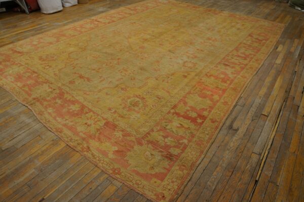 Distressed golden-yellow rug with faded floral patterns and coral borders covers old wooden floorboards.