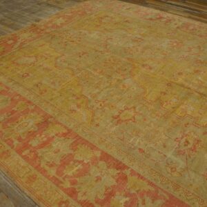 Distressed ochre and salmon area rug featuring a traditional medallion pattern on wide plank wood floors.