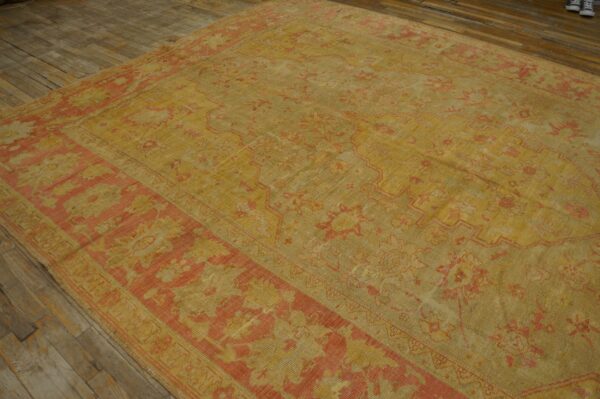 Distressed ochre and salmon area rug featuring a traditional medallion pattern on wide plank wood floors.