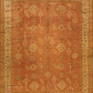 Rust-colored rug with golden geometric and floral patterns and an ornate light beige border.