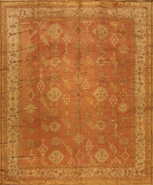 Rust-colored rug with golden geometric and floral patterns and an ornate light beige border.