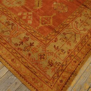 Geometric rug in rust and gold colors showing tribal motifs on worn wood flooring.
