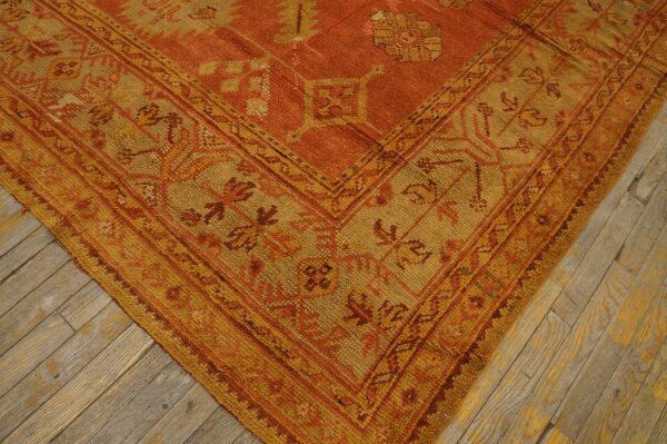 Geometric rug in rust and gold colors showing tribal motifs on worn wood flooring.