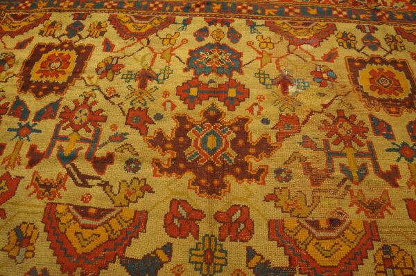 Textured rug detail with angular tribal motifs in gold, rust, and teal on a bright yellow field.