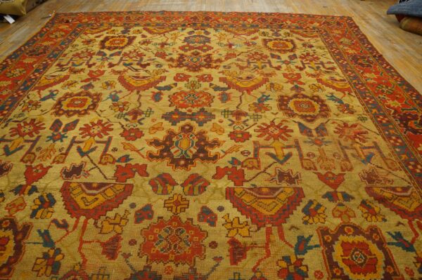 Gold rug with red, yellow, and blue geometric and stylized traditional motifs on wood floor.