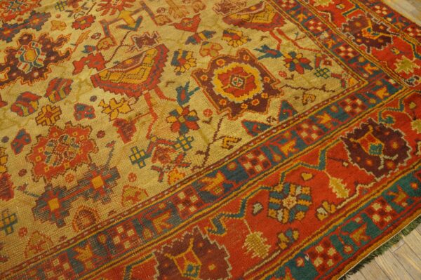 Low-pile rug with a gold field, stylized red and teal motifs, and a thick, vibrant red border.