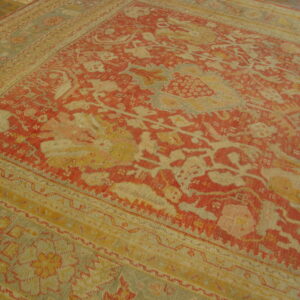 Low-pile rug with intricate red and beige traditional design on a dark wood floor.